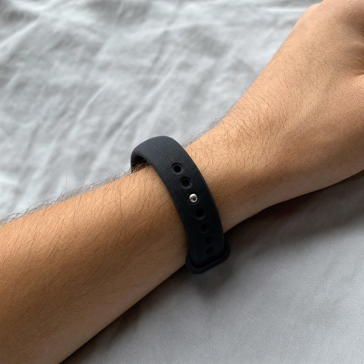 Close-up of the NOVIQ Wake silicone band fastened on an adult wrist, showing the size and strap holes